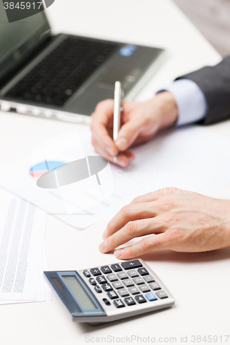 Image of close up of businessman with laptop and papers