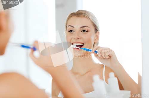 Image of woman with toothbrush cleaning teeth at bathroom