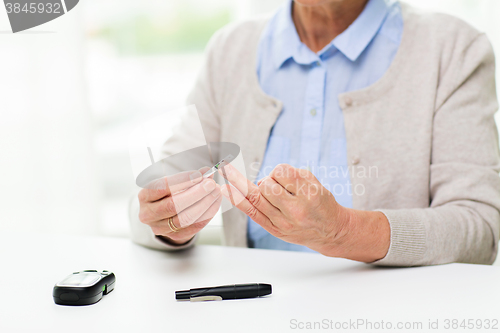 Image of senior woman with glucometer checking blood sugar