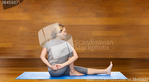 Image of woman making yoga in twist pose on mat