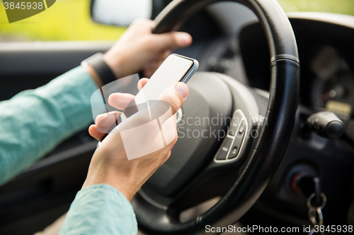 Image of close up of man hand with smartphone driving car