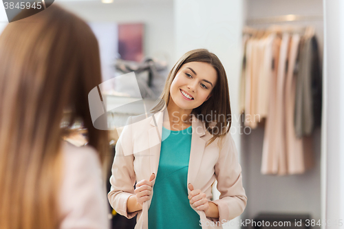 Image of happy woman posing at mirror in clothing store