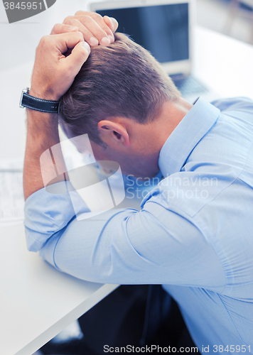 Image of stressed businessman with papers at work