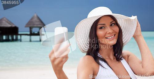 Image of young woman taking selfie with smartphone