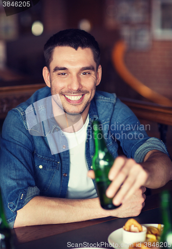 Image of happy young man drinking beer at bar or pub