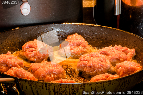 Image of Raw meatballs on a frying pan