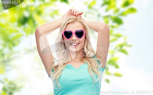 Image of happy young woman in heart shape sunglasses