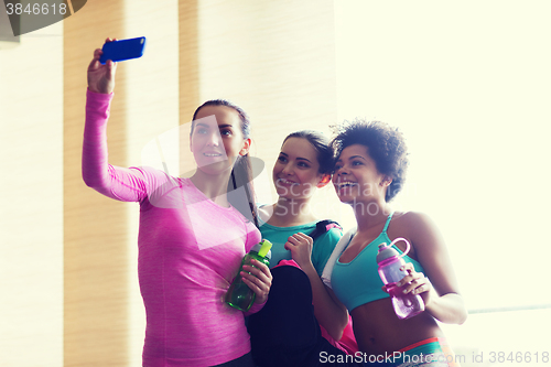 Image of happy women with smartphone taking selfie in gym