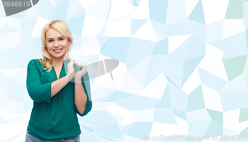 Image of smiling young woman in shirt showing heart shape