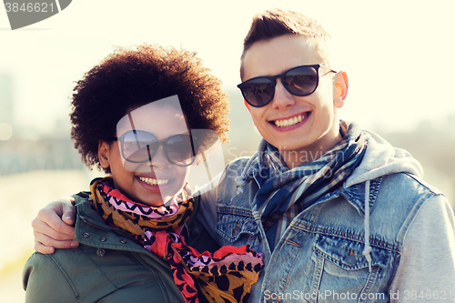 Image of happy teenage friends in shades hugging outdoors