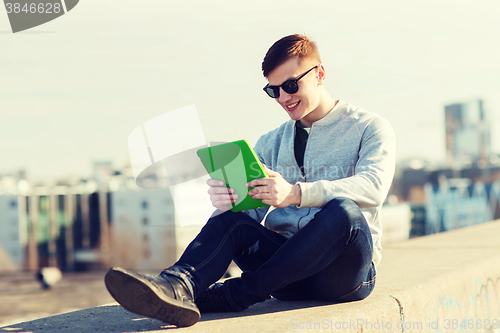 Image of happy young man with tablet pc outdoors