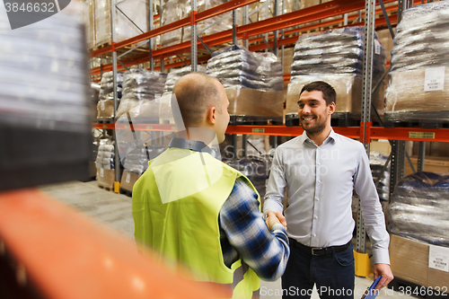 Image of worker and businessmen with clipboard at warehouse