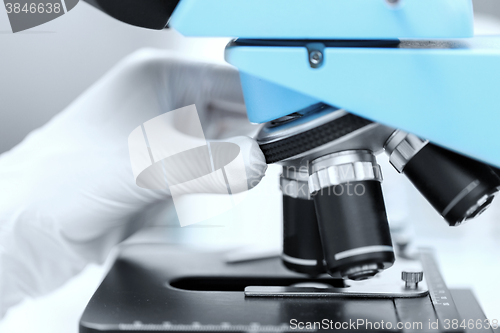 Image of close up of scientist hand setting microscope