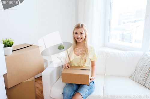 Image of smiling young woman with cardboard box at home