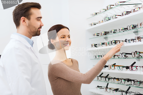 Image of woman showing glasses to optician at optics store