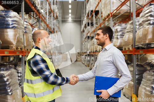 Image of worker and businessmen with clipboard at warehouse