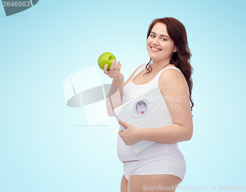 Image of happy young plus size woman holding scales