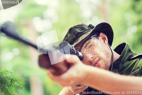 Image of young soldier or hunter with gun in forest