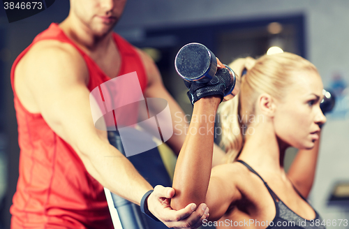 Image of man and woman with dumbbells in gym