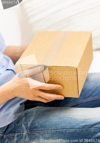 Image of close up of man with cardboard box parcel at home