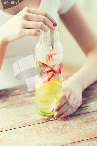 Image of close up of woman with fruit water in glass bottle