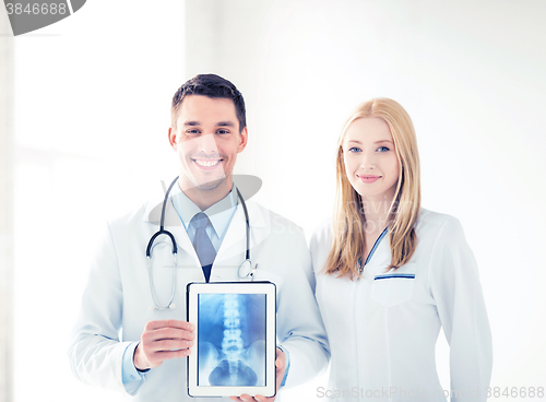 Image of two doctors showing x-ray on tablet pc