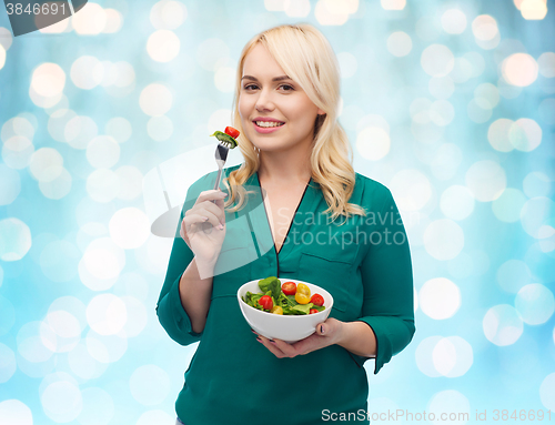 Image of smiling young woman eating vegetable salad