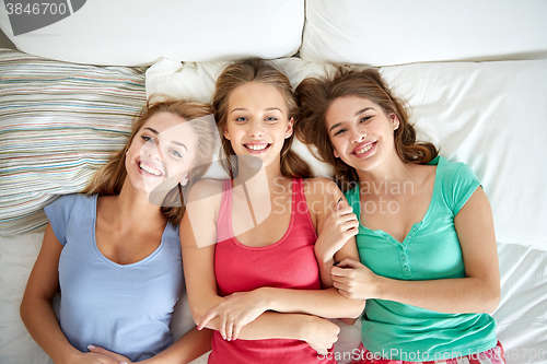 Image of happy young women in bed at home pajama party