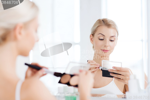 Image of woman with makeup brush and foundation at bathroom