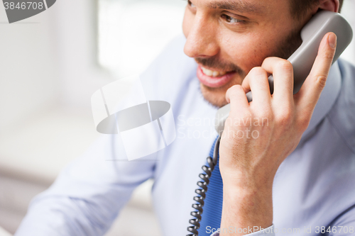 Image of happy businessman calling on phone at office