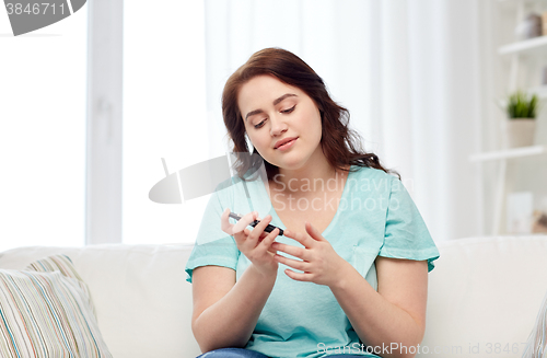 Image of plus size woman making blood test by glucometer