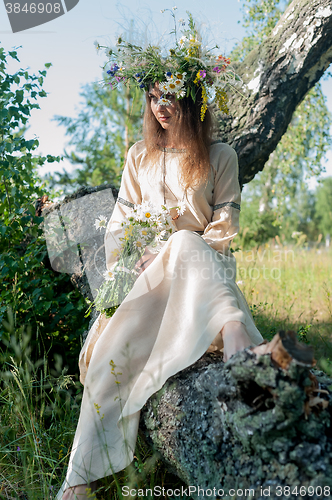 Image of Woman in national dress and flower wreath on tree