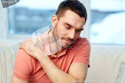 Image of unhappy man suffering from neck pain at home