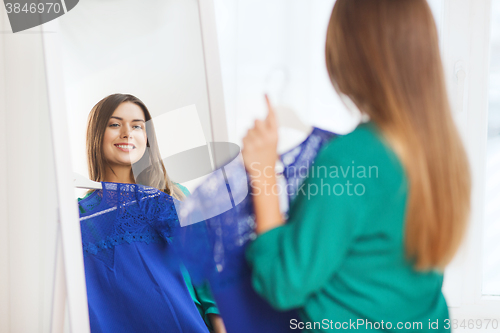 Image of happy woman choosing clothes at home wardrobe