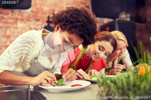 Image of happy women cooking and decorating dishes