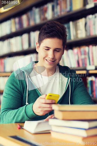 Image of male student with smartphone texting in library