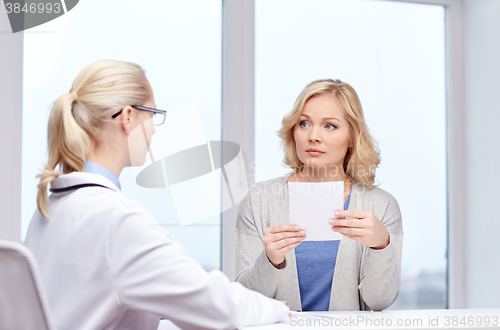 Image of doctor giving prescription to woman at hospital