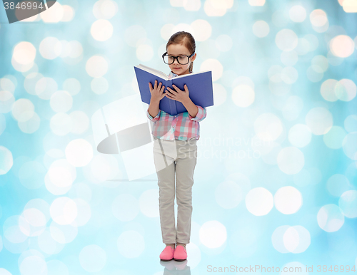 Image of happy little girl in eyeglasses reading book