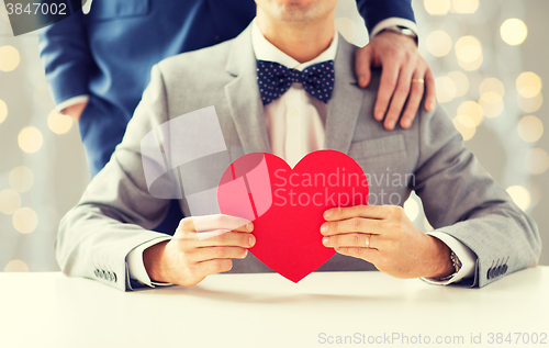 Image of close up of male gay couple with red heart