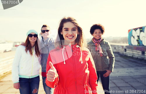 Image of happy teenage friends showing thumbs up on street