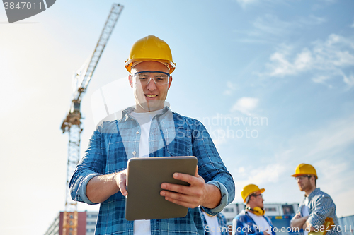 Image of builder in hardhat with tablet pc at construction