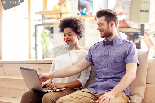 Image of happy creative team with laptop in office