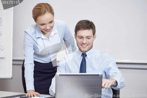 Image of smiling businesspeople with laptop in office