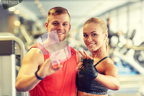 Image of smiling man and woman showing ok hand sign in gym