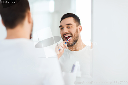 Image of man with toothbrush cleaning teeth at bathroom