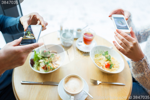 Image of close up of couple picturing food by smartphone