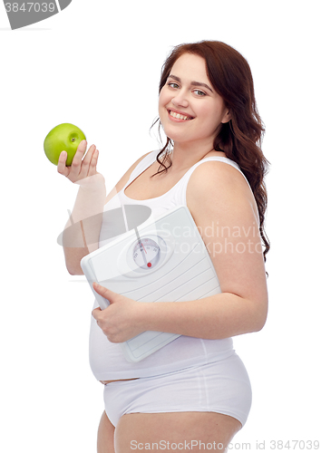 Image of happy young plus size woman holding scales