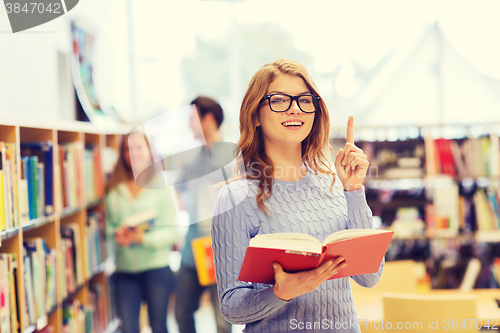 Image of happy student girl or woman with book in library