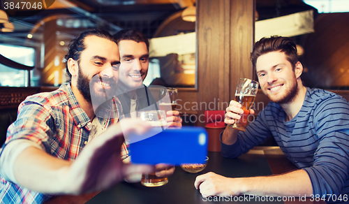 Image of male friends with smartphone drinking beer at bar