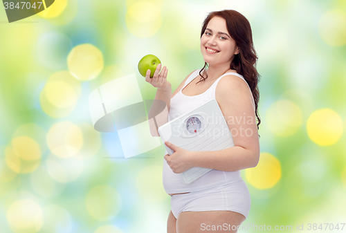 Image of happy young plus size woman holding scales